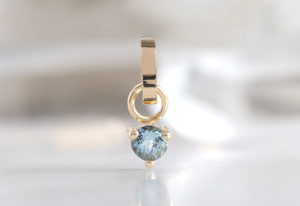 10k Yellow Gold Aquamarine Birthstone Charm on White Marble Tile