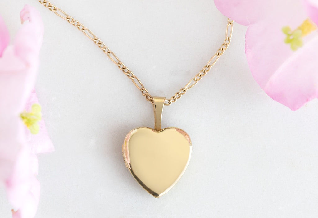 Yellow Gold Filled Mini Sweetheart Locket Necklace Close Up on White Marble Tile with pink flowers