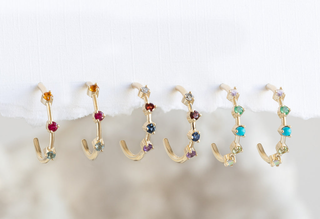 Custom Multi-Birthstone Hoops hanging on white textured paper 