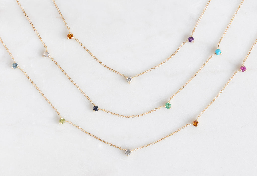 Custom Multi-Birthstone Necklaces on White Marble Tile