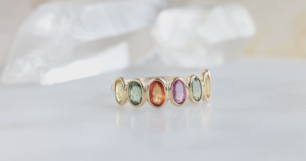 yellow gold Rainbow Gemstone Eternity Ring on white marble tile