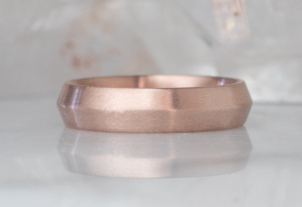 Rose Gold The Knife Edge Wedding Band on White Marble Tile