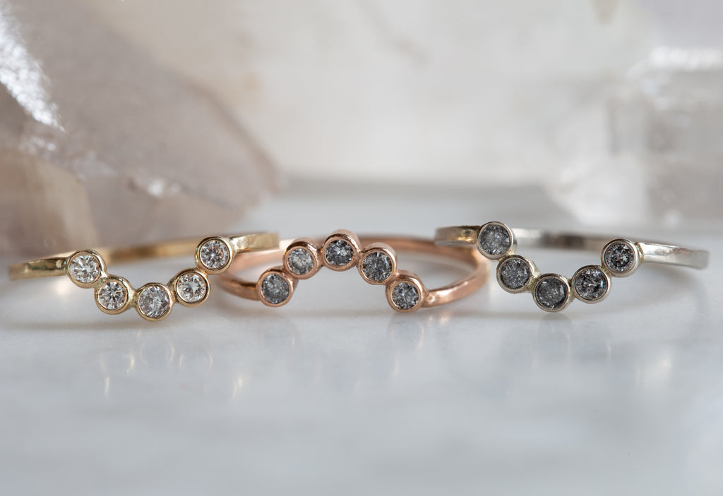 Three Diamond Bezel Arc Rings in yellow, white and rose gold on white marble tile