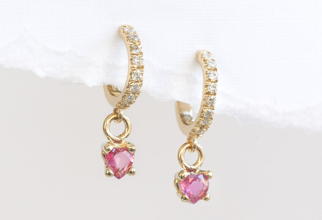 Yellow Gold Ruby Heart + Diamond Huggie Studs Hanging on Textured White Paper