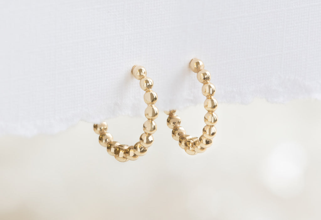 Yellow Beaded Huggie Hoops Hanging on Textured Paper