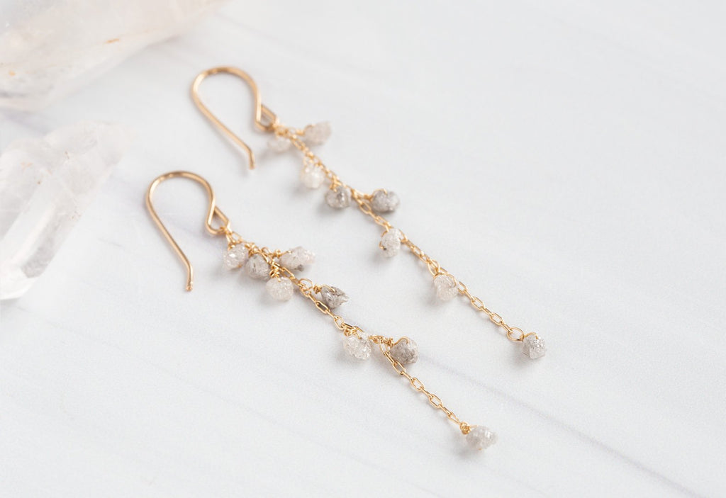 Yellow Gold Rough Diamond Cascade Earrings hanging on white marble tile