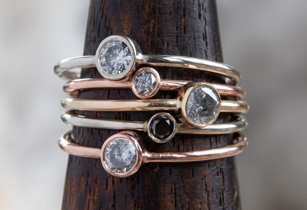 Teensy Custom Diamond Stacking Rings on dark wooden mandrel