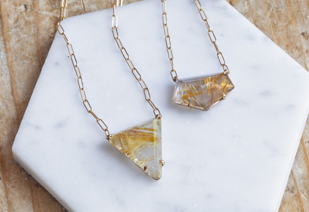 Two Rutilated Quartz Necklaces on White Marble Tile