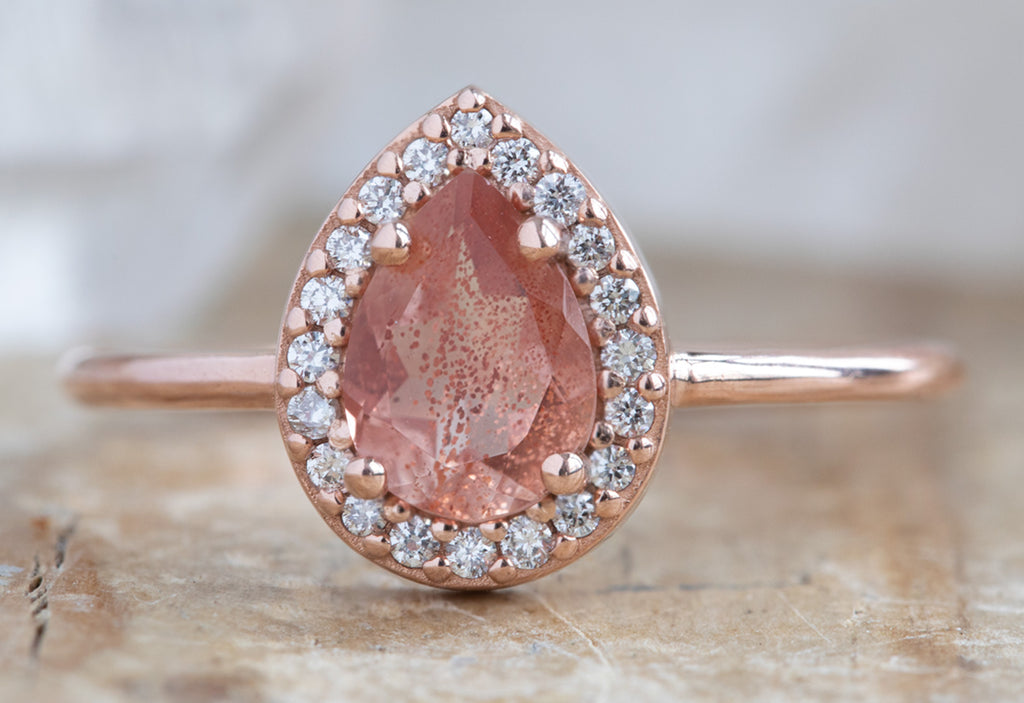 The Dahlia Ring with a Pear-Cut Sunstone on Wood Table